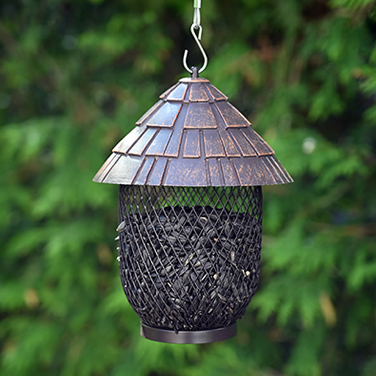 Shingled Mesh Bird Feeder, a metal mesh cylinder with a shingle-style lid, filled with sunflower seeds, designed for 360-degree feeding of small clinging birds.