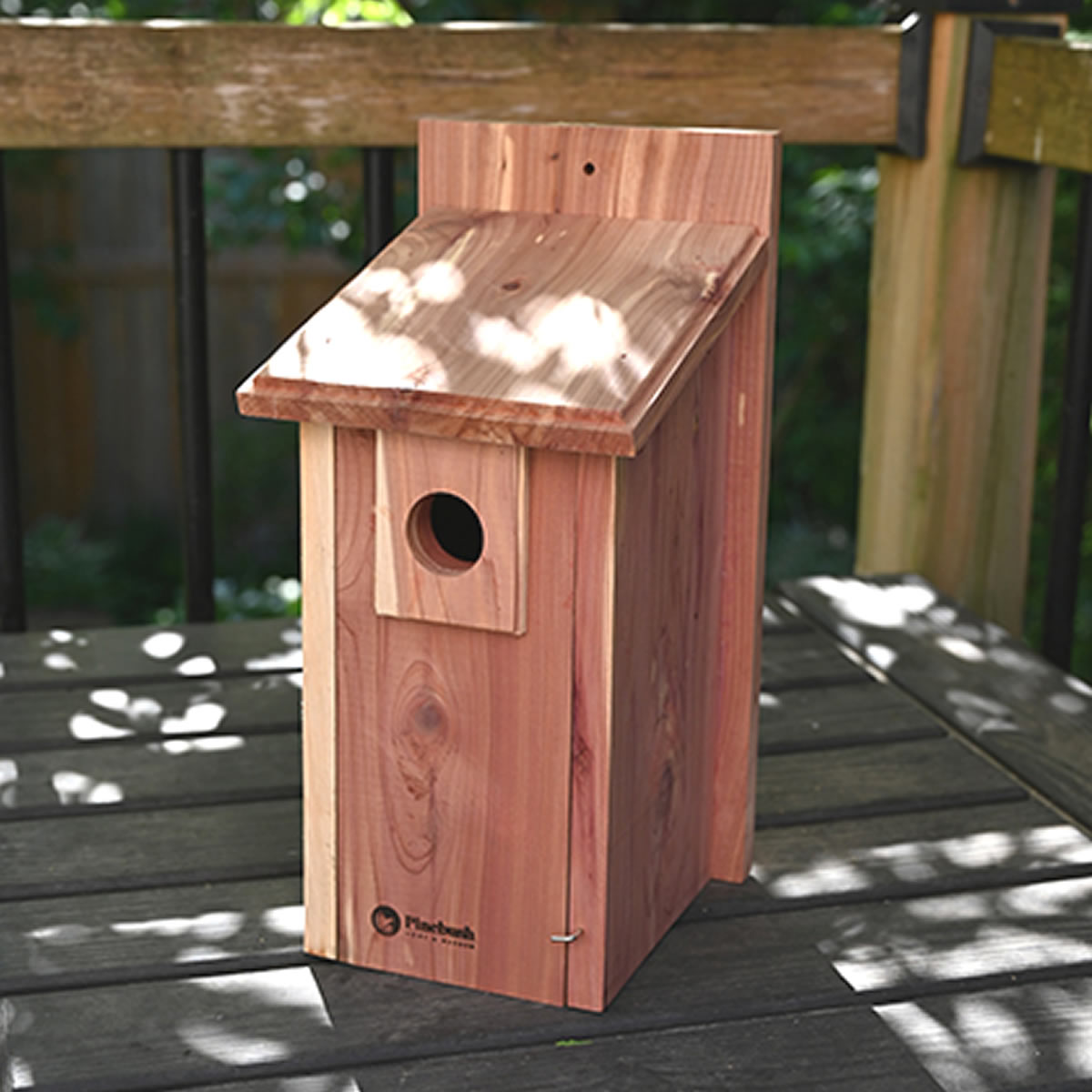 Backyard Nesting Box: Simple cedar birdhouse with sloped roof and 1-1/4 entry hole, designed for small birds, features a front clean-out door on deck railing.