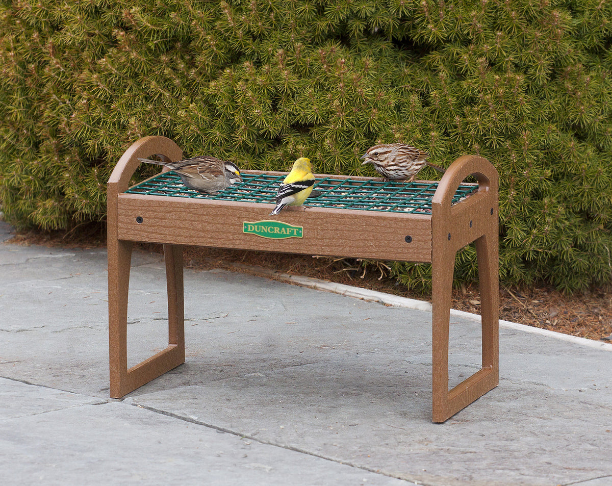 Duncraft EZ Move Ground Platform Feeder with birds on a bench, featuring a raised tray and wire grid insert to prevent seed flicking.