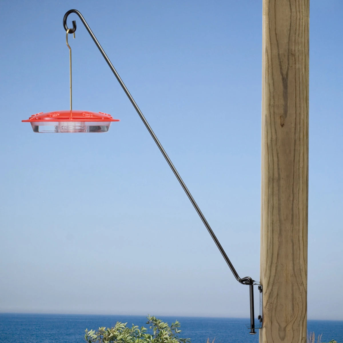 Five Position Wall Bracket with red hummingbird feeder, suspended from wooden post. Black metal arm swings 180 degrees, designed for easy filling and optimal positioning.