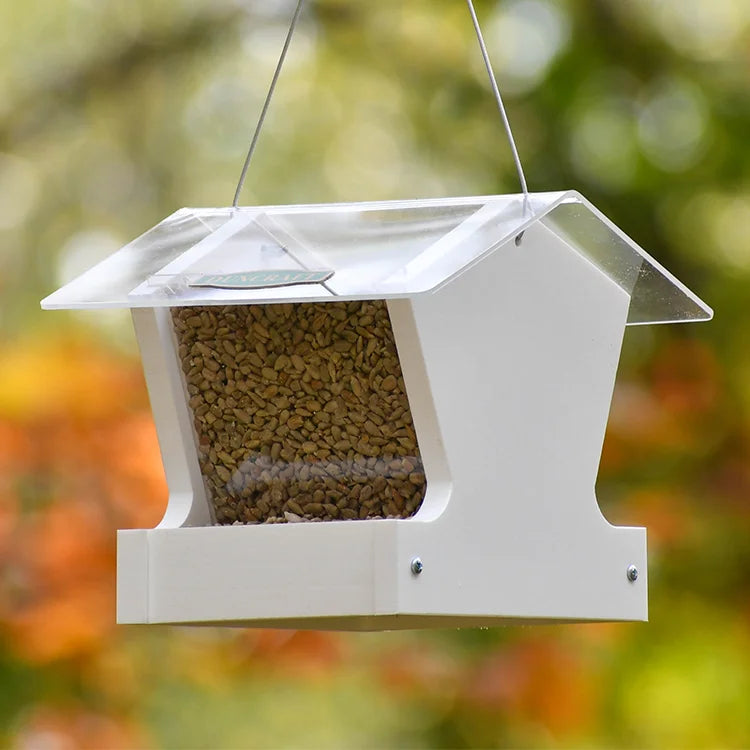 Duncraft Heritage Hopper Bird Feeder, White: House-shaped feeder with clear front, metal mesh floor, and wide roof, designed for cardinals, chickadees, and finches.