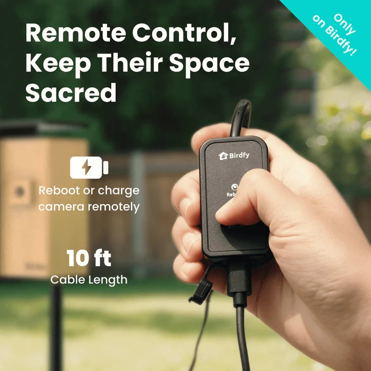 Hand holding a remote control device with text about remote control and cable length, set against a blurred outdoor background.