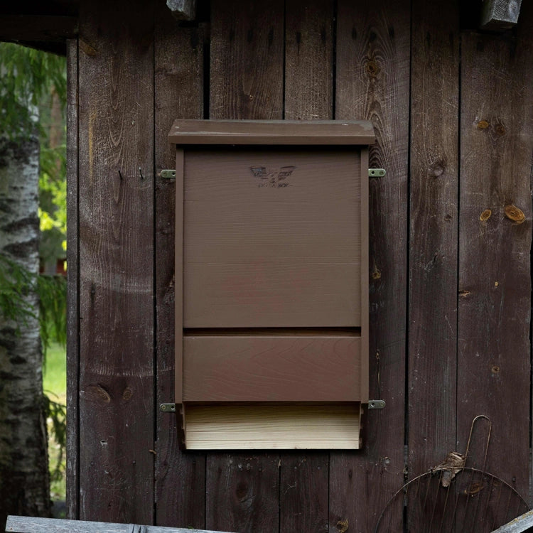 Cedar bat house mounted on the side of a brown barn.