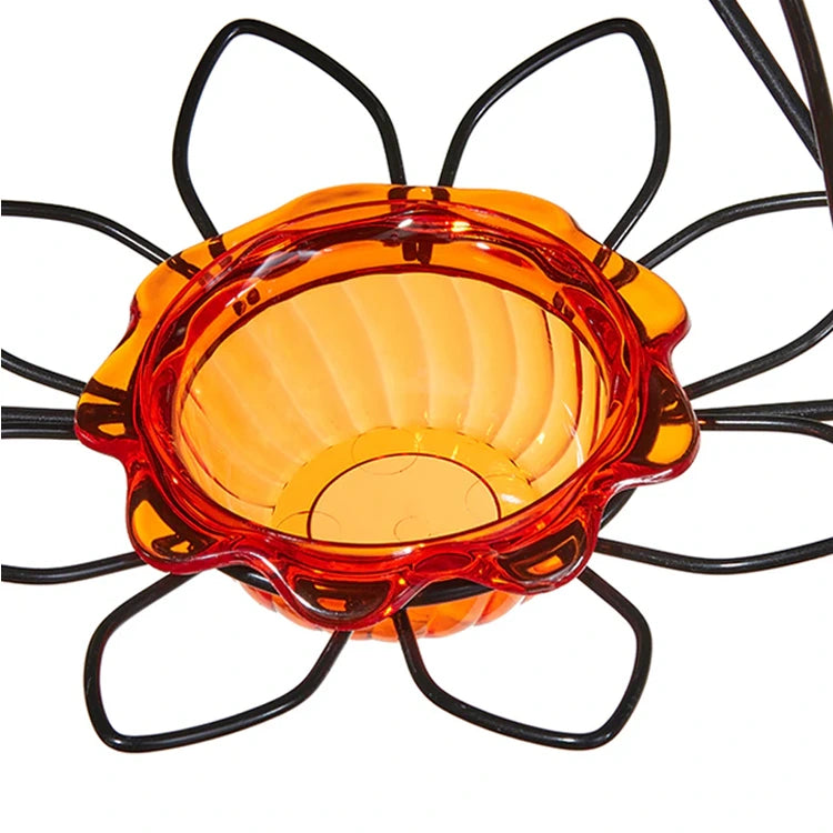 Orange flower-shaped bird feeder dish close up.