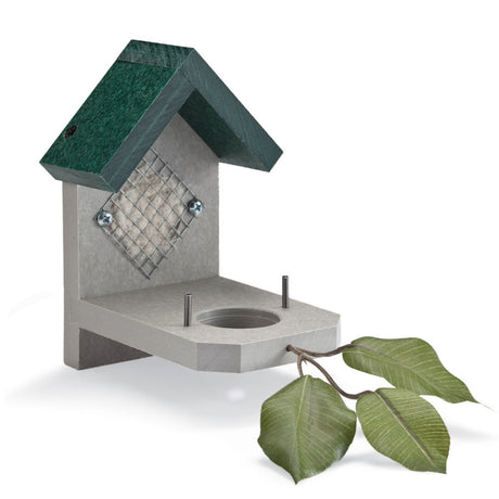 House-shaped bird feeder with green roof, gray platform, metal grid for suet, round cut-out for fat ball, and decorative artificial twig.