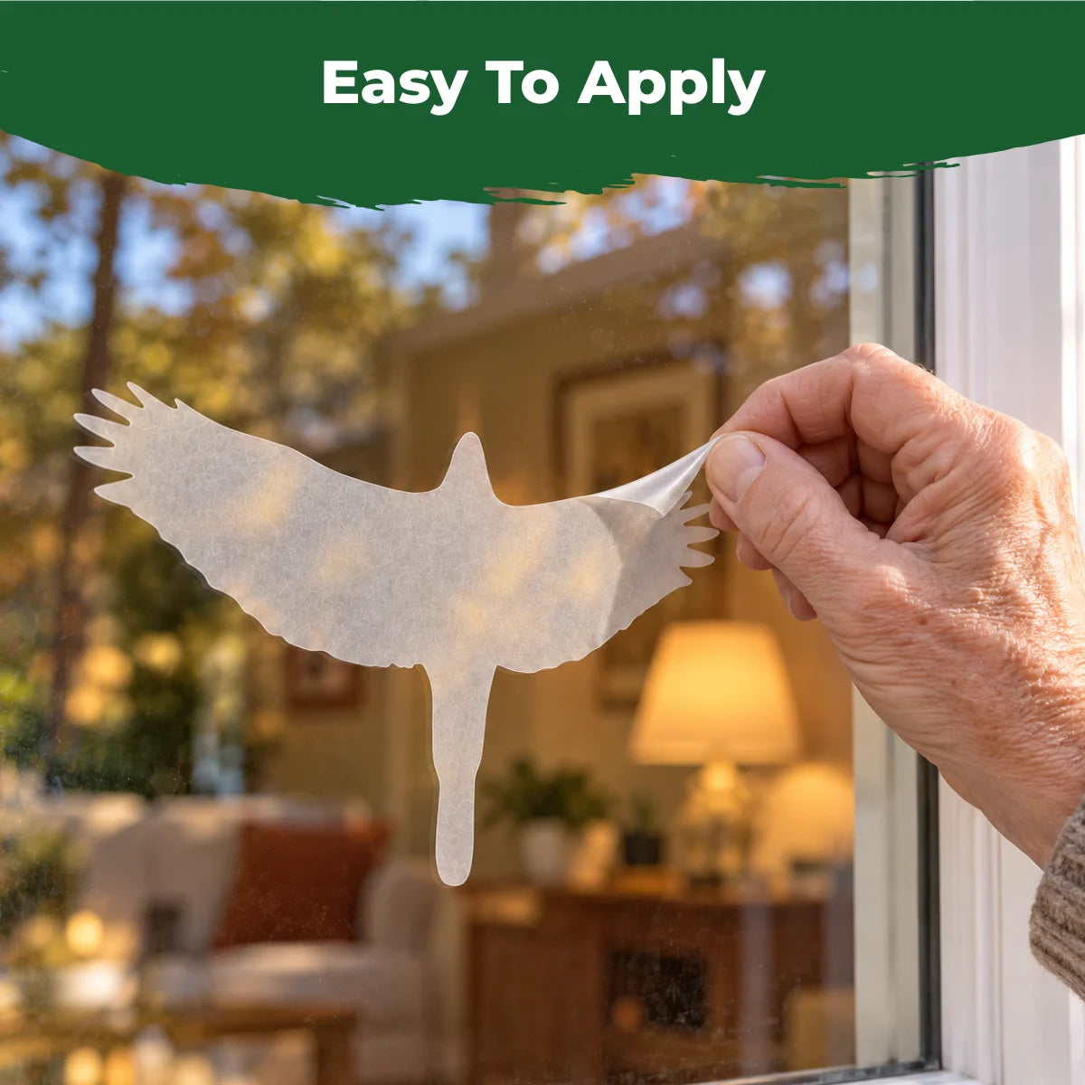 Close-up of a hand applying a translucent hawk bird-safe decal to the outside of a window.