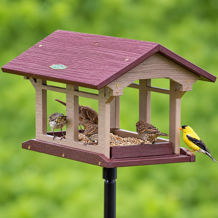 Duncraft Covered Bridge Feeder with Pole & Twister, featuring birds feeding from all sides on a durable platform with built-in perches and drainage.