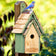 Duncraft Bluebird Manor House, Sage: Wooden birdhouse with a shingled roof, bluebird perched on top, entry hole in front, and DUNCRAFT logo visible.