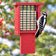 Downy Woodpecker perched on a red recycled plastic tail prop suet feeder with metal mesh cage and suet cake against a softly blurred winter backyard background.