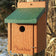 Woodlink Going Green™ Wren House mounted on a tree, featuring a 1-inch entry hole and made from recycled green and brown plastic for sturdy, predator-proof nesting.