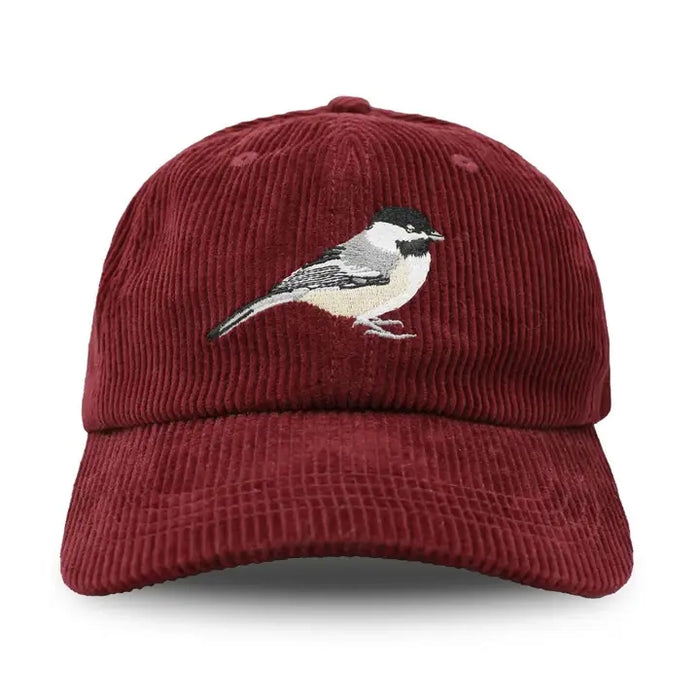Burgundy corduroy baseball cap with embroidered Black-capped Chickadee, featuring an unstructured 6-panel crown, curved bill, and adjustable fabric strap.