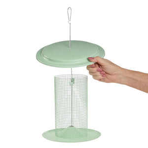 Hand lifting the lid of a sage green sunflower seed bird feeder for easy filling.
