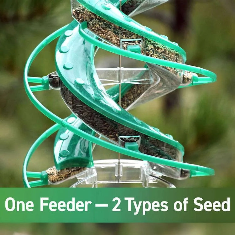 Green spiral bird feeder with seeds on a blurred natural background