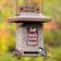 Rustic Farmhouse Train Feeding Station Squirrel-Resistant Feeder with a bird perched on it, featuring weight-sensitive perches and a locking roof, hanging outdoors.
