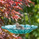 Turquoise handblown recycled glass hanging bird bath with dahlia-inspired floral design suspended from decorative metal chain.