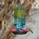 Seafoam Ombre Column Antique Hummingbird Feeder hanging outdoors, featuring an embossed glass reservoir with a seafoam green to blue ombre finish and flower-shaped feeding ports.