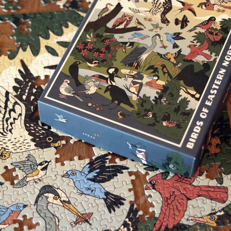 Partially assembled Birds of Eastern North America Puzzle on table, featuring illustrations of various bird species, with box showcasing the same artwork.