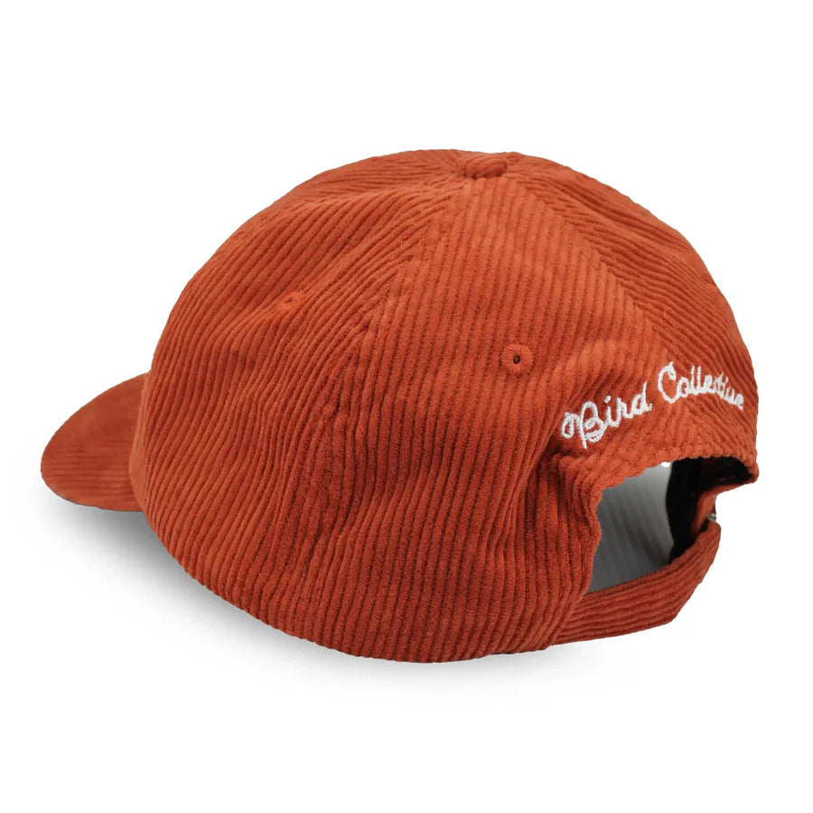 Chickadee Corduroy Hat, Burgundy: Six-panel burnt-orange corduroy cap with curved brim, adjustable strap, and Great Horned Owl embroidery, ideal for birdwatching enthusiasts.